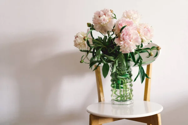 リビングルームの白い椅子にピンクの牡丹の花束 母の日 愛とロマンチックな概念 — ストック写真