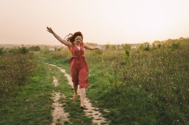 Çekici kızıl saçlı, şirin yüzlü bir kadının portreleri. Gün batımında tarlada kameraya poz veren kız.