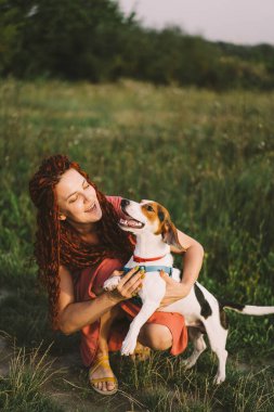 Güzel kadın parkta Jack Russell köpeğiyle oynuyor. Hayvanlar, arkadaşlık, insanlar ve aşk kavramı. Bir kadın çimlere uzanıyor ve Jack Russell Terrier ile oynuyor.