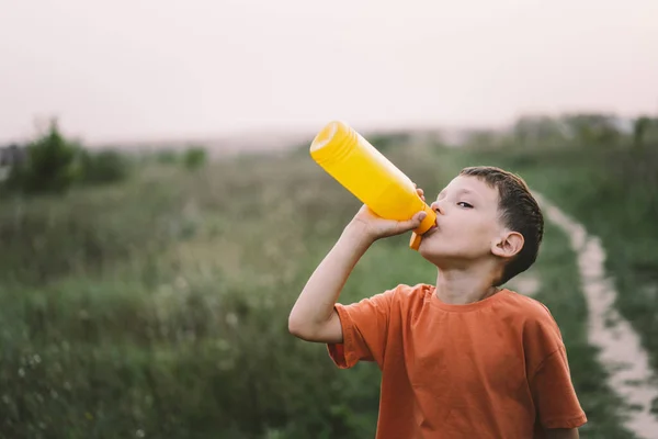 Bambino Beve Acqua Una Bottiglia Arancione Mentre Cammina Salute Del — Foto Stock