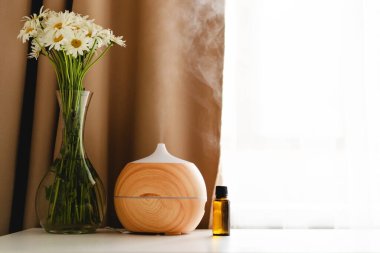 Aromatherapy concept. Aroma oil diffuser on the table against the window. Air freshener. Ultrasonic aroma diffuser for home