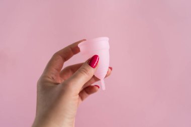 Silikon adet bardağı. Kadın sağlığı ve alternatif hijyen. Pembe arka planda çiçekli bir fincan. Sıfır atık alternatif