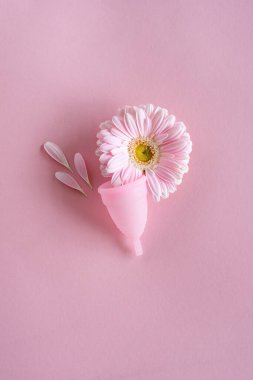 Silikon adet bardağı. Kadın sağlığı ve alternatif hijyen. Pembe arka planda çiçekli bir fincan. Sıfır atık alternatif