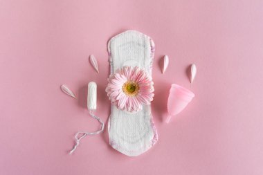 Adet dönemi konsepti. Hijyenik beyaz kadın pedi, adet bardağı ve pembe çiçekli tampon. Adet görme, koruma. Kadın Sağlığı
