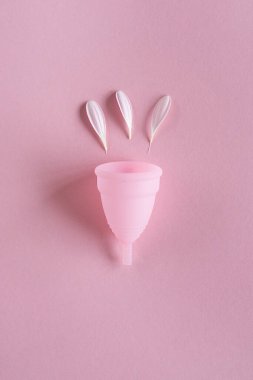 Silikon adet bardağı. Kadın sağlığı ve alternatif hijyen. Pembe arka planda çiçekli bir fincan. Sıfır atık alternatif