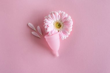 Silikon adet bardağı. Kadın sağlığı ve alternatif hijyen. Pembe arka planda çiçekli bir fincan. Sıfır atık alternatif