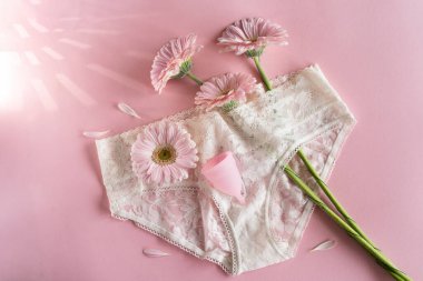 Silikon adet bardağı. Kadın sağlığı ve alternatif hijyen. Pembe arka planda çiçekli bir fincan. Sıfır atık alternatif