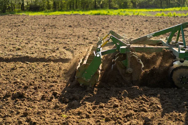 stock image The tractor drives across the field and cultivates the land. Agricultural vehicle works in countryside. Sowing is the process of planting seeds in the ground as part of the early spring time