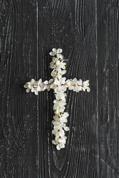 Cross symbolizing the death and resurrection of Jesus Christ, spring flowers on a wood background
