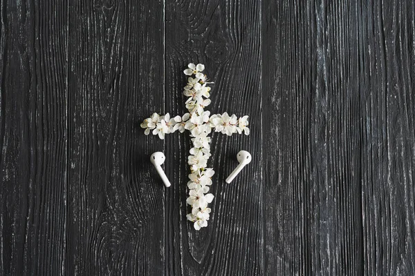 Spring flowers in the shape of a cross. The concept of Christian music. Cross symbolizing the death and resurrection of Jesus Christ, spring flowers on a wooden background