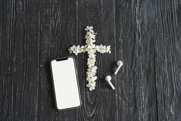 Spring flowers in the shape of a cross. The concept of Christian music. Cross symbolizing the death and resurrection of Jesus Christ, spring flowers on a wooden background