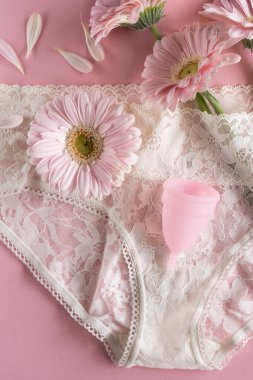 Silikon adet bardağı. Kadın sağlığı ve alternatif hijyen. Pembe arka planda çiçekli bir fincan. Sıfır atık alternatif