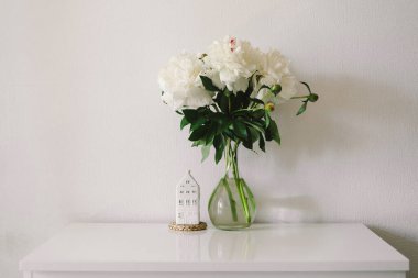 Oturma odasının iç kısımlarında hala hayat detayları var. Beyaz şakayıklı vazo. Sıcak bahar konsepti.