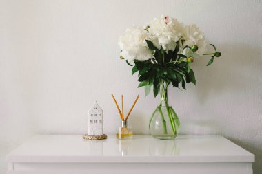 Oturma odasının iç kısımlarında hala hayat detayları var. Beyaz şakayıklı tütsü çubukları ve vazo. Ev için çevre dostu bir parfüm. Sıcak bahar konsepti.