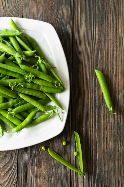 stock image Fresh green peas on a wooden background. Summer crop of peas.