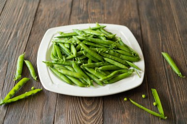 Ahşap arka planda taze bezelyeler. Yaz bezelye mahsulü.