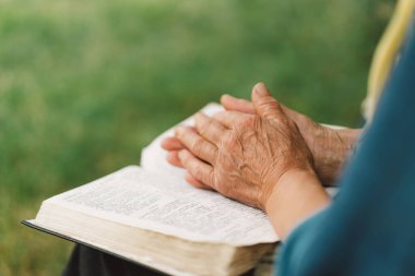 İncil, kitap okumak ya da Hristiyanlık dininde umut, yardım ya da destek için dua eden yaşlı bir kadın. Dua ya da kıdemli kişi açık havada ruhani edebiyatta Tanrı 'ya ibadet ediyor ya da okuyor.