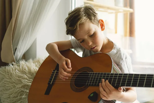 Милый Мальчик Учится Играть Классической Гитаре Подоконнике Возле Окна Уютный — стоковое фото