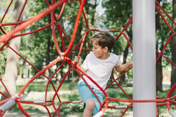 stock image Happy boy child playing in rope spider web at playground. Childrens sports.