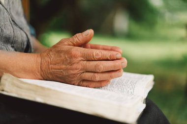 İncil, kitap okumak ya da Hristiyanlık dininde umut, yardım ya da destek için dua eden yaşlı bir kadın. Dua ya da kıdemli kişi açık havada ruhani edebiyatta Tanrı 'ya ibadet ediyor ya da okuyor.