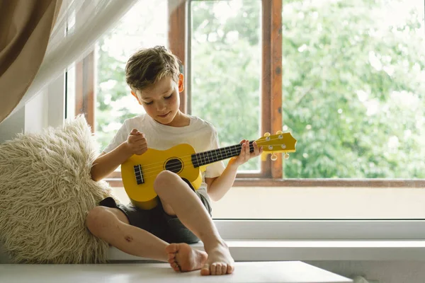 Cute Boy Learns Play Yellow Ukulele Guitar Windowsill Window Cozy — Stock Photo, Image