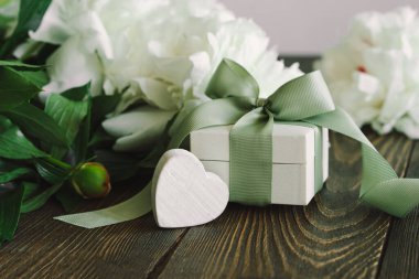 Ahşap arka planda hediye kutuları olan bir buket güzel beyaz şakayık. Şık bir çiçek selamı. Anneler Günü