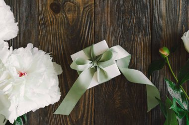 Ahşap arka planda hediye kutuları olan bir buket güzel beyaz şakayık. Şık bir çiçek selamı. Anneler Günü