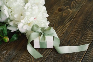 Ahşap arka planda hediye kutuları olan bir buket güzel beyaz şakayık. Şık bir çiçek selamı. Anneler Günü