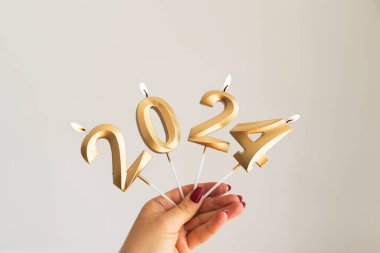 Mutlu yıllar 2024. Kız yeni yıl mumlarını 2024 numaralı formda tutuyor. Noel bayramı kutlaması. Yeni yıl konsepti.