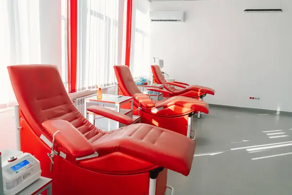 stock image Red armchairs for sitting in donation center. Blood transfusion station for taking blood from donors