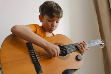 Tatlı çocuk evde klasik gitar çalmayı öğreniyor. Rahat bir ev. Yaz tatili yaşam tarzı.