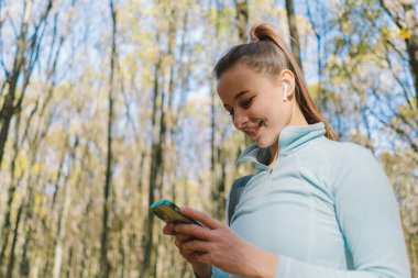 Güzel bir kız telefonu spor ya da yoga için kullanır. Vücut pozitifliği, kadınlar için spor, uyum, sağlıklı yaşam tarzı, kendini sevme ve refah..