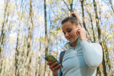 Güzel bir kız telefonu spor ya da yoga için kullanır. Vücut pozitifliği, kadınlar için spor, uyum, sağlıklı yaşam tarzı, kendini sevme ve refah..