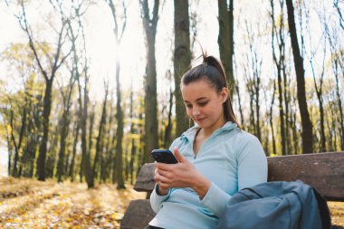 Güzel bir kız telefonu spor ya da yoga için kullanır. Vücut pozitifliği, kadınlar için spor, uyum, sağlıklı yaşam tarzı, kendini sevme ve refah..