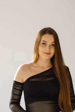 Beyaz arka planda kameraya gülümseyen güzel, neşeli bir kızın portresi. Esmer kız.