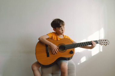 Tatlı çocuk evde klasik gitar çalmayı öğreniyor. Rahat bir ev. Yaz tatili yaşam tarzı.