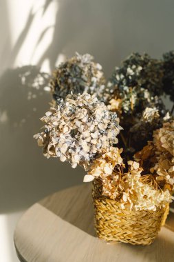 Hasır sepetin içinde kurumuş çiçeklerin kompozisyonu ev dekorasyonu olarak kullanılıyor..