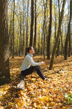 Güneşli bir sonbahar ormanında müzik dinleyip dışarıda spor yapan güzel bir kız. Vücut pozitifliği, kadınlar için spor, uyum, sağlıklı yaşam tarzı, kendini sevme ve refah..