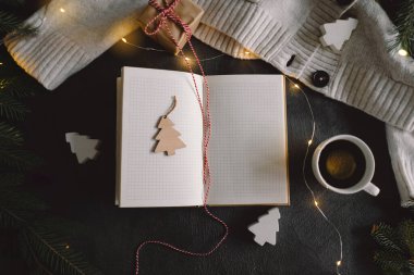 2024 sayılı yeni yıl kararları masada. 2024 karar listesi süveter ve Noel süslemeleri ile birlikte gri arka planda ışıklar bokeh. Hedefler, çözümler, plan, kontrol listesi konsepti.