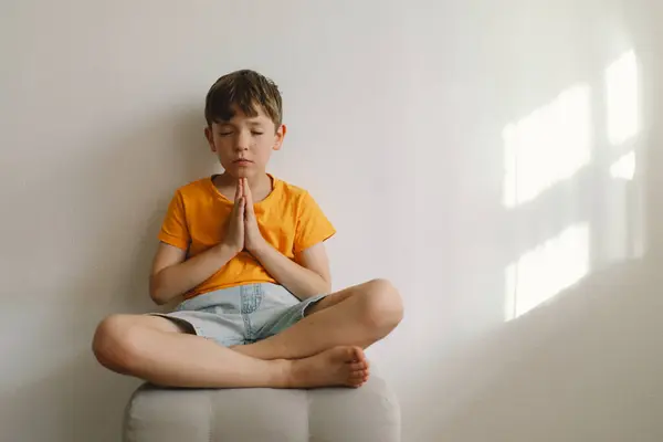 stock image A boy in an orange T-shirt prays at home. Reading the Holy Bible. Concept for faith, spirituality and religion. Peace, hope.