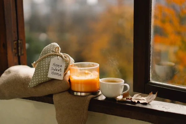 Sweet Home. Still life details in home on a wooden window. Sweater, candle, hot coffee and autumn decor. Autumn home decor. Cozy fall mood. Cozy autumn or winter concept.