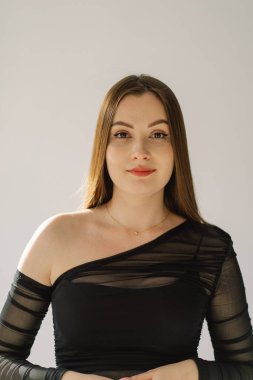 Beyaz arka planda kameraya gülümseyen güzel, neşeli bir kızın portresi. Esmer kız.