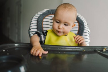 Sağlam beslenmiş küçük bir çocuk. Küçük kız parmak yemeği yiyor ve sebze tabağını karıştırıyor. Bebek sütten kesme BLW kendini besleme.