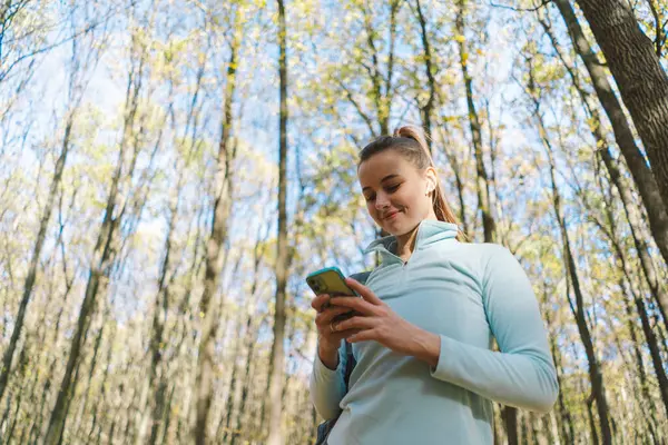 Güzel bir kız telefonu spor ya da yoga için kullanır. Vücut pozitifliği, kadınlar için spor, uyum, sağlıklı yaşam tarzı, kendini sevme ve refah..