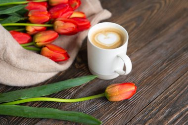 Taze turuncu laleler ve bahar kompozisyonlu kapuçino kupası. Sevgililer Günü, Kadınlar Günü ve Anneler Günü için fotokopi alanı olan tebrik kartı..