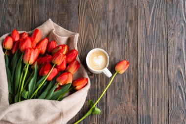 Taze turuncu laleler ve bahar kompozisyonlu kapuçino kupası. Sevgililer Günü, Kadınlar Günü ve Anneler Günü için fotokopi alanı olan tebrik kartı..