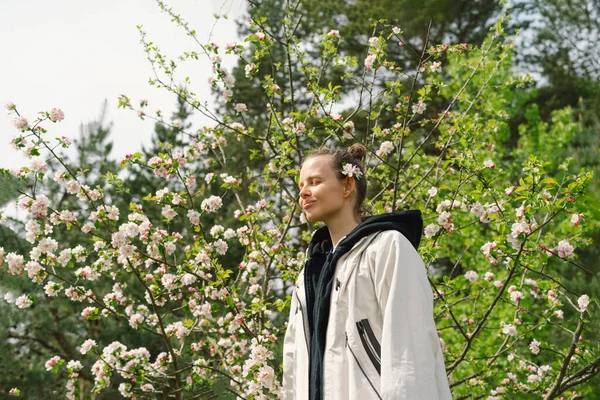 Bahar çiçekleriyle güzel genç bir kadın doğanın tadını çıkarıyor ve bahar bahçesinde gülüyor. Elma ağacının dalını tutan kadın. Özgürlük ve mutluluk kavramı. İlkbahar.