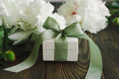 Ahşap arka planda hediye kutuları olan bir buket güzel beyaz şakayık. Şık bir çiçek selamı. Anneler Günü