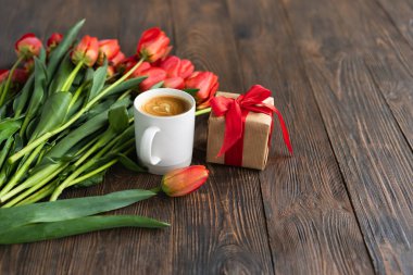 Taze turuncu laleler ve bahar kompozisyonlu kapuçino kupası. Sevgililer Günü, Kadınlar Günü ve Anneler Günü için fotokopi alanı olan tebrik kartı..