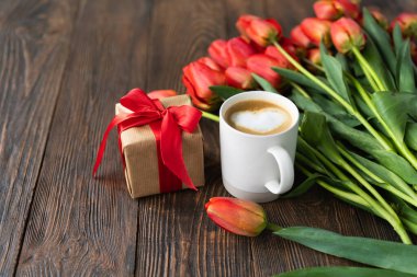 Taze turuncu laleler ve bahar kompozisyonlu kapuçino kupası. Sevgililer Günü, Kadınlar Günü ve Anneler Günü için fotokopi alanı olan tebrik kartı..